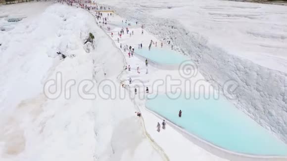 白色石灰石梯田上成群的游客帕穆卡莱土耳其空中镜头视频的预览图