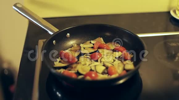 男性手在锅里搅拌蔬菜炒西红柿洋葱茄子视频的预览图