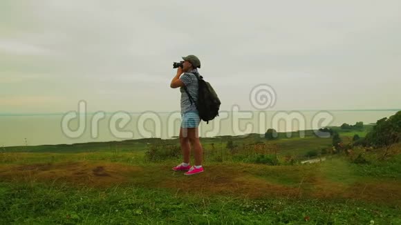 背着背包的女旅行者在山上拍了一张湖的照片视频的预览图