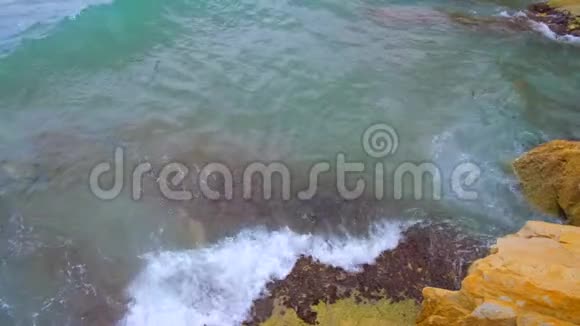 青绿色的波浪在岩石上破碎海面上的光波视频的预览图