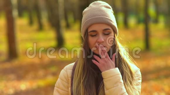 秋天公园里年轻迷人的女孩他看着相机微笑表现出不同的情绪用手触摸他的脸视频的预览图