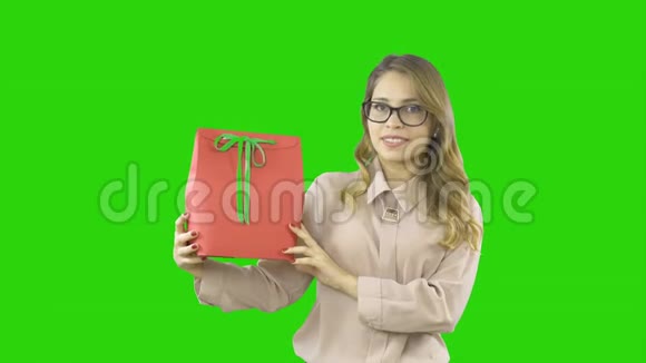 一个年轻女子的欢乐情绪她在一个孤立的地方拍摄一份礼物一份礼物放在一个带绿色丝带的红色盒子里视频的预览图