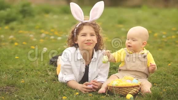 可爱的孩子们在草地上拿着复活节篮子复活节概念浅绿色黄色视频的预览图