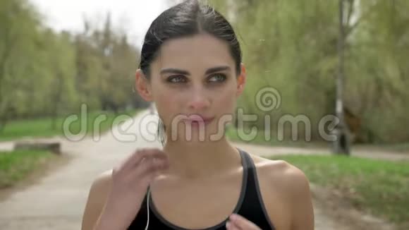 年轻的运动女孩戴着耳机在公园里跑步健康的生活方式运动观念视频的预览图