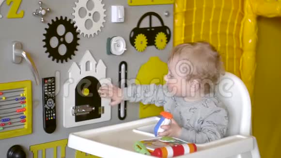 可爱的小男孩在墙上玩忙碌的木板教育玩具视频的预览图
