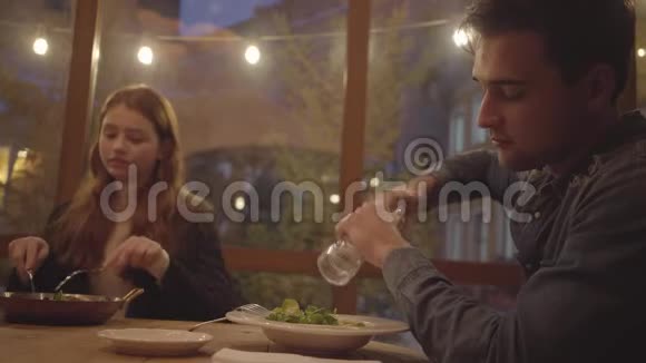 两个朋友坐在靠近窗户的现代咖啡馆里吃食物红发的年轻女人吃深铝的饭视频的预览图