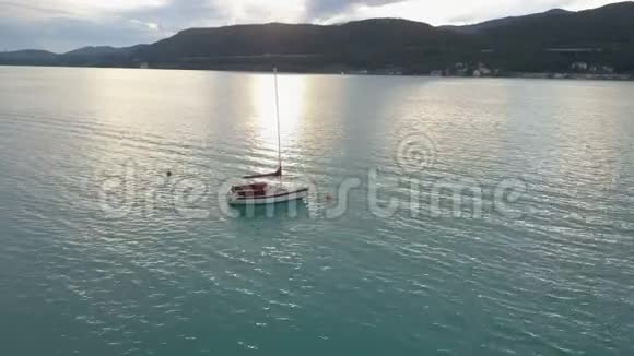 一艘小型游艇在山上的一个大湖上的鸟瞰图船在湖上移动克拉根福卡林西亚奥地利视频的预览图