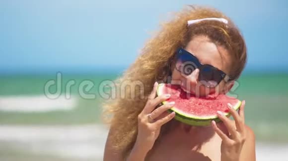 微笑的女人在海滩上吃西瓜女人吃美味的夏天水果暑假快乐视频的预览图