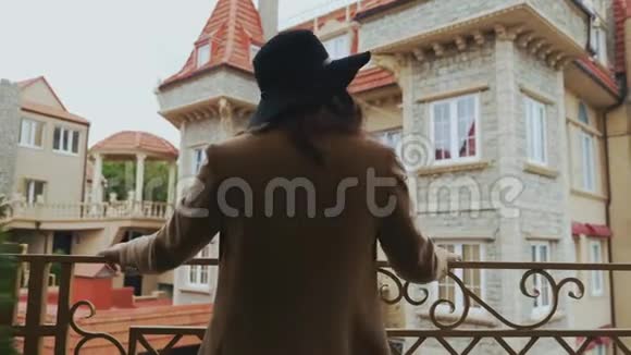 一个穿着长外套戴着黑色时髦帽子的开朗女孩第一次来到欧洲向路人挥手致意视频的预览图