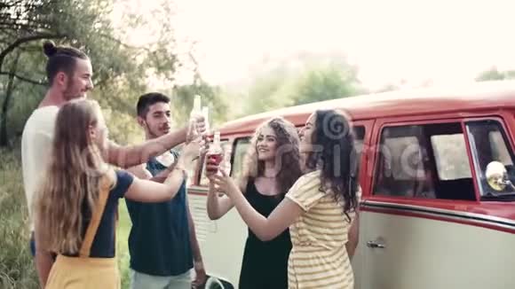 一群朋友站在户外穿过乡村的路上叮叮作响的瓶子视频的预览图