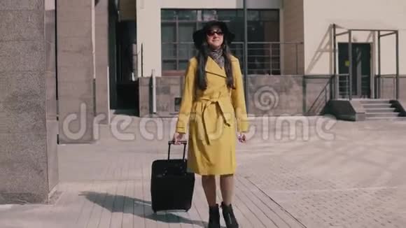 穿着黄色雨衣帽和眼镜的时髦女孩带着行李视频的预览图
