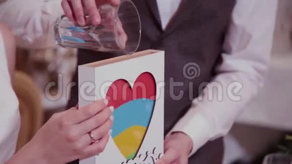 婚礼上的沙礼新郎在婚礼上关上装满不同颜色沙子的玻璃容器管视频的预览图