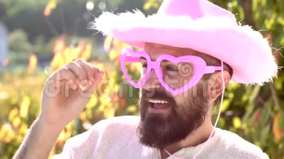 带着滑稽时髦的粉红色太阳镜和滑稽的粉红色帽子的嬉皮士有趣的脸惊讶和有趣的人的肖像视频的预览图