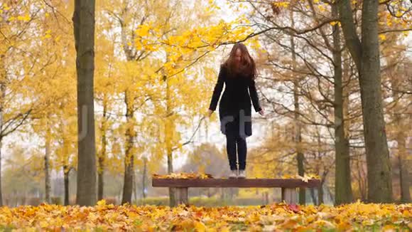 快乐的女人在公园里跳黄色落叶视频的预览图
