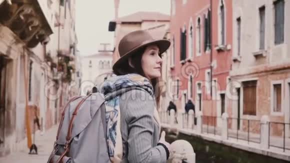 快乐美丽的女游客在威尼斯意大利慢动作沿着运河街道散步视频的预览图