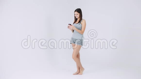 fitmodel使用手机健身应用程序穿着白色背景的运动服聊天视频的预览图