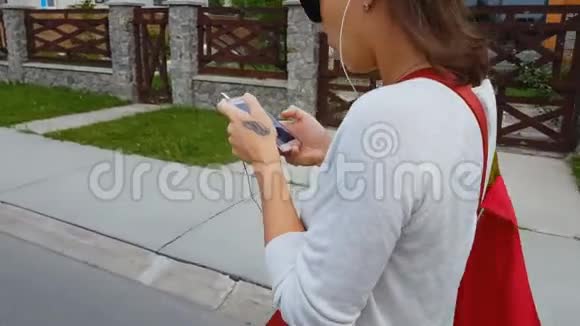 女学生耳机看智能手机应用程序步行街生命危险视频的预览图