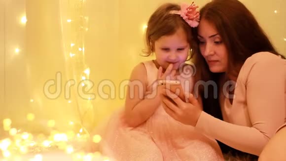 母女俩在智能手机上看视频的背景是灯光视频的预览图