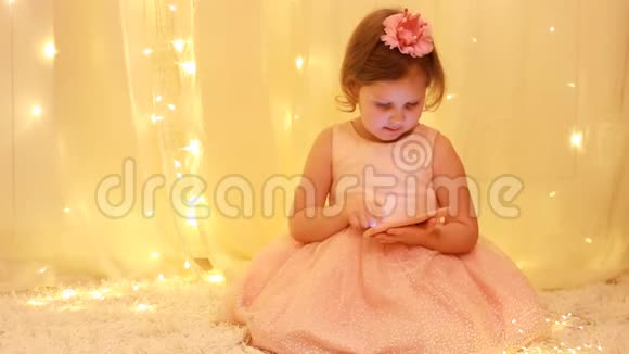 小女孩玩智能手机宝贝公主在手机上观看视频的背景灯视频的预览图