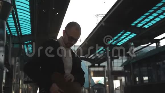 火车站里一个戴着眼镜和包的人检查他的护照和火车票视频的预览图