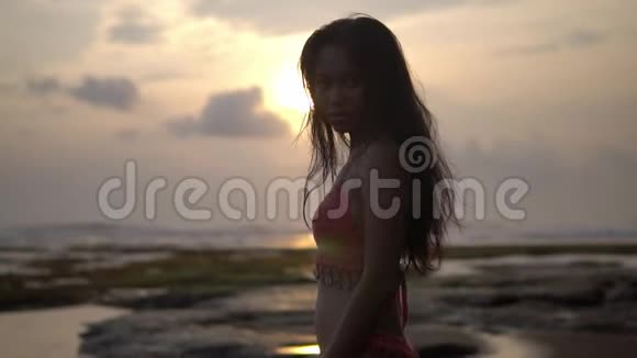 伟大的亚洲比基尼女郎走在傍晚的海边把她的背转到镜头前视频的预览图