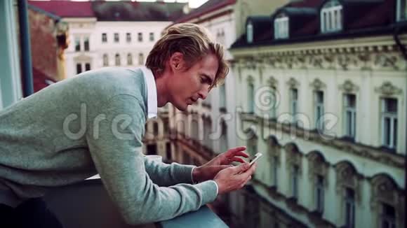 有智能手机的年轻人站在城市的阳台上发短信视频的预览图