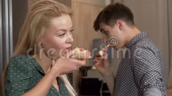 迷人的女人吃着美味的披萨和男朋友对着镜头微笑视频的预览图