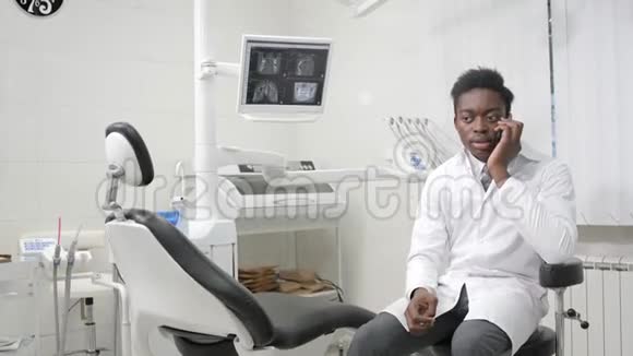 年轻的非裔美国男性牙医在牙科办公室在电话里和病人说话医学卫生视频的预览图