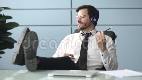 快乐商人戴着耳机在工作场所听音乐视频的预览图