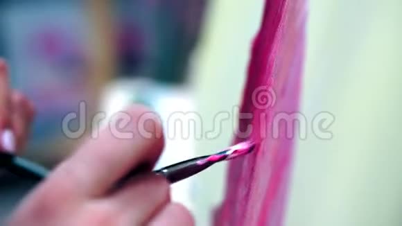 这位艺术家在画布上作画涂上一层宽的画笔帆布站在画架上视频的预览图