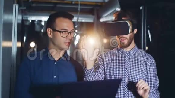 两名工程师使用VR眼镜和笔记本电脑在一个数据中心关闭视频的预览图
