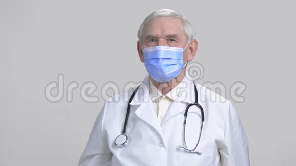 老医生带着注射器在灰色的孤立背景下视频的预览图