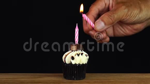 男人在木制桌子上点燃生日巧克力蛋糕上的蜡烛视频的预览图