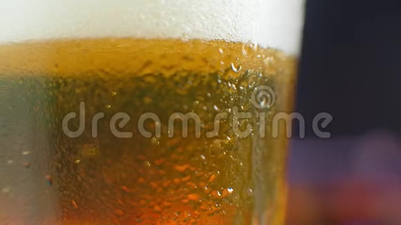 宏观拍摄的一个啤酒杯与冷啤酒气泡上升的玻璃慢动作啤酒气泡视频的预览图