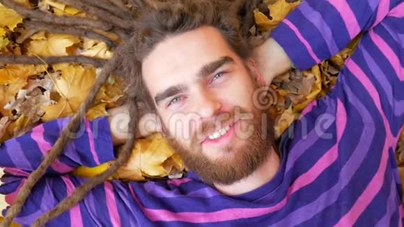 微笑的人躺在秋天公园的落叶上视频的预览图