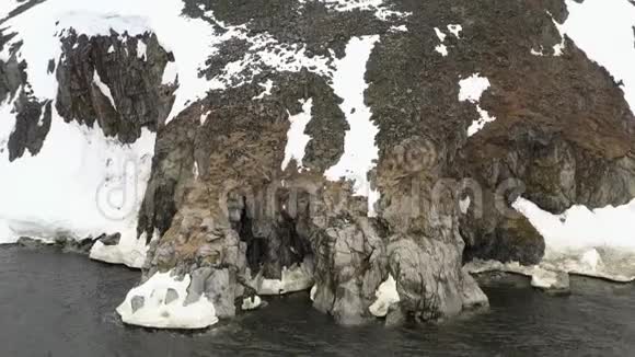 海岸上有一个洞穴的岩石被雪覆盖视频的预览图