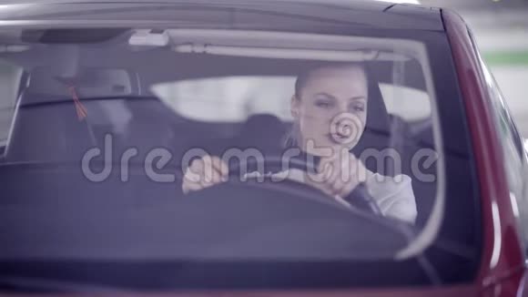 刚开始吸烟时一个梳着马尾辫的可爱女性坐在红色的车里视频的预览图