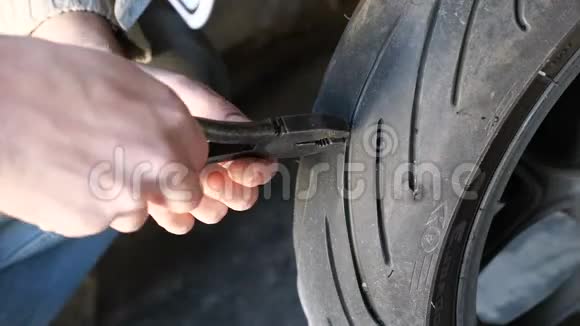用钳子把摩托车轮轮胎上的钉子拔出来视频的预览图