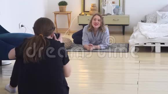 专业摄影棚的年轻摄影师在地毯上拍摄微笑模特的照片专业照片视频的预览图