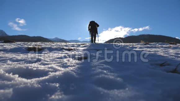 年轻的徒步旅行者在雪地上用棍棒行走的后景无法辨认的人在雪地上跋涉视频的预览图