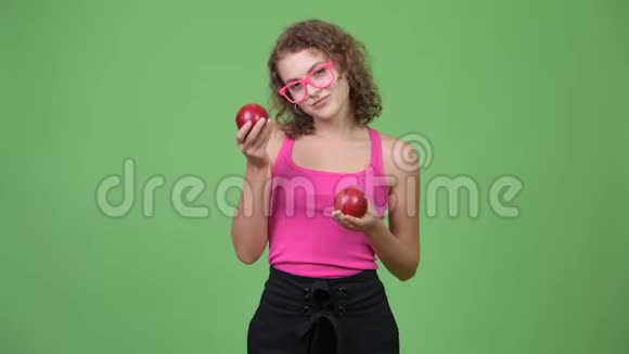 年轻漂亮的书呆子女人展示两个红苹果视频的预览图