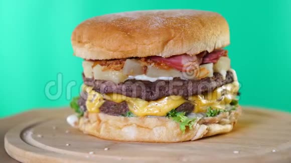 牛肉汉堡奶酪酱汁和蔬菜旋转在木板前面的绿色屏幕背景视频的预览图