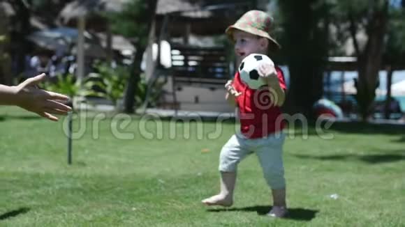 可爱的小男孩玩着一个足球拥抱着他的母亲库存录像视频的预览图