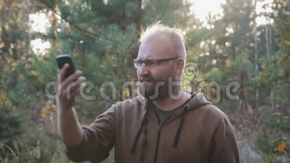 一个留着胡子的年轻人在树林里寻找手机信号视频的预览图