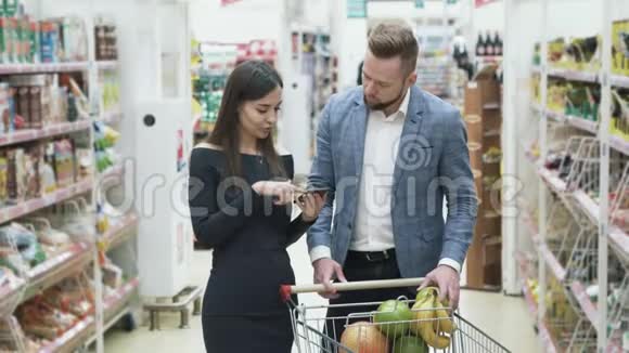 女人用智能手机检查产品清单男人选择水果在超市闻一闻视频的预览图