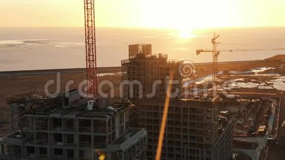 一架正在建造的无人机在日落时分从一栋多层建筑上射击建筑工人在屋顶上行走视频的预览图