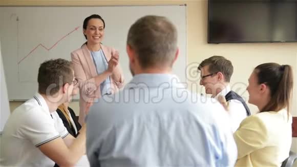不同的员工和女性教练在企业商业培训研讨会上举手视频的预览图