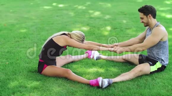 健身教练在公园的热身训练中帮助女性伸展腿部视频的预览图