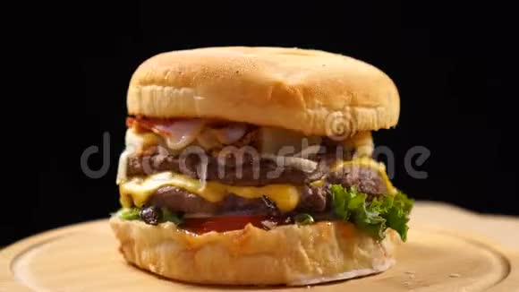 牛肉多汁的汉堡在黑色背景的桌子上快速旋转视频的预览图