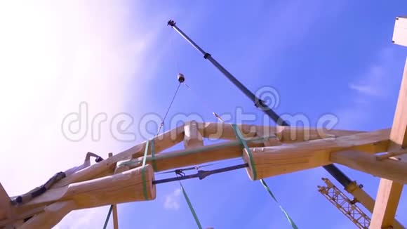 在蓝天背景下起重机吊起的圆柱形木梁的底部视图剪辑程序视频的预览图